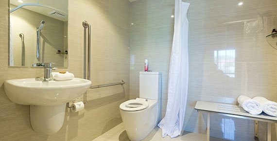 fully tiled bathroom with handrails and flat floor